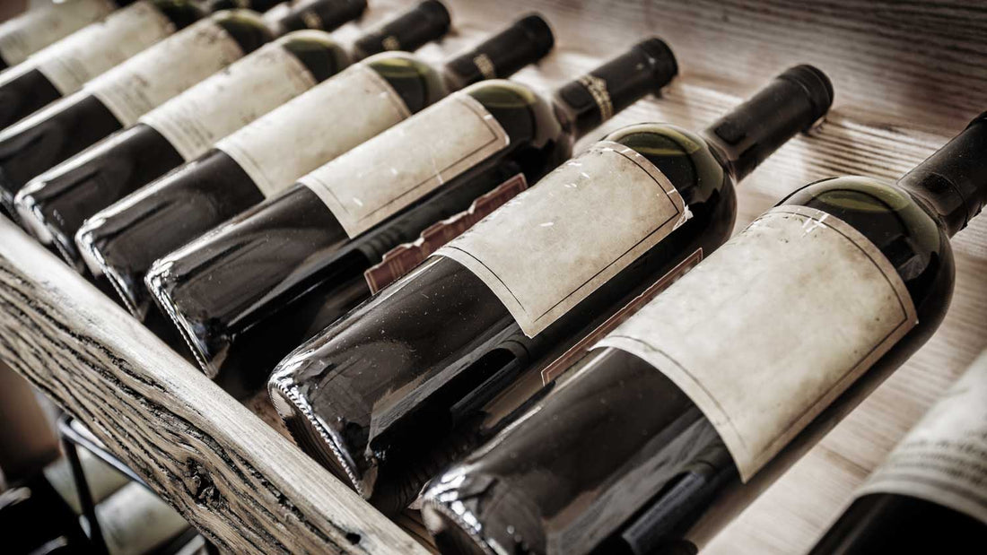 Alte Weinflaschen liegen im Weinregal