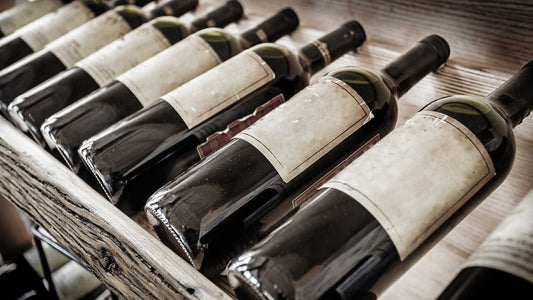 Alte Weinflaschen liegen im Weinregal