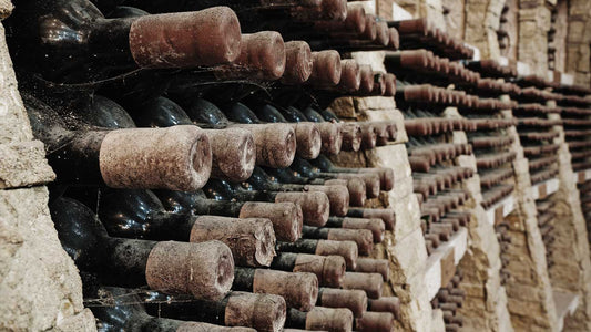 Alte Weinflaschen liegen in einer Reihe im Weinregal in einem Weinkeller