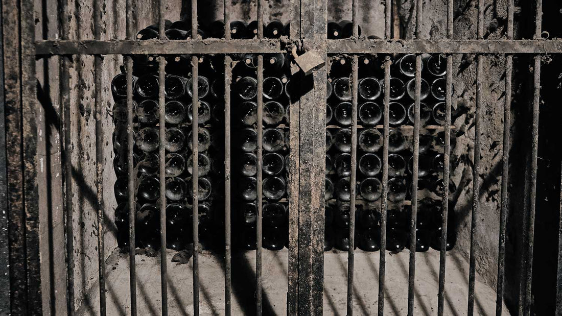 Alter Wein lagert in einem Weinkeller, der mit einem Gitter verschlossen ist