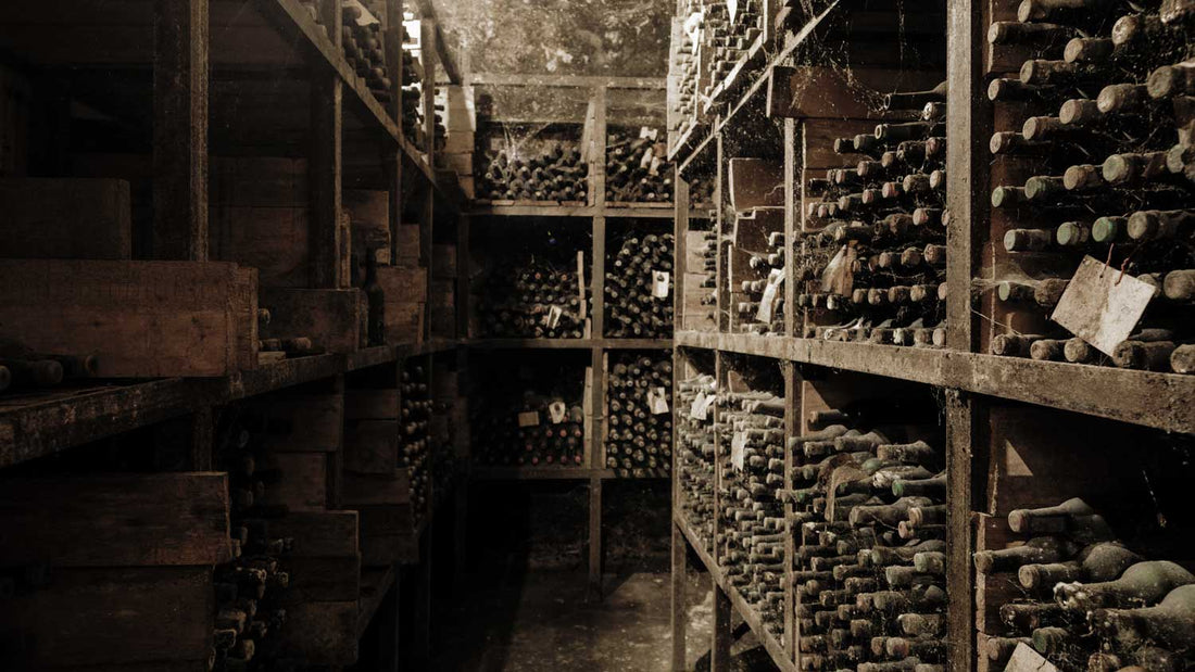 Alte Weinflaschen liegen im Weinregal in einem Weinkeller