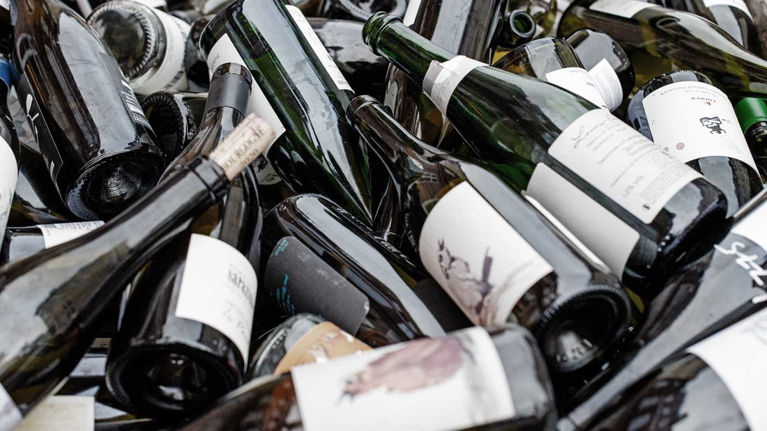 Viele leere Weinflaschen aus Glas liegen willkürlich herum.