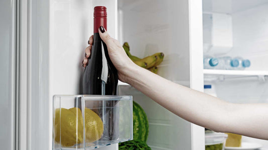 Eine Frau greift in den Kühlschrank nach einer Weinflasche