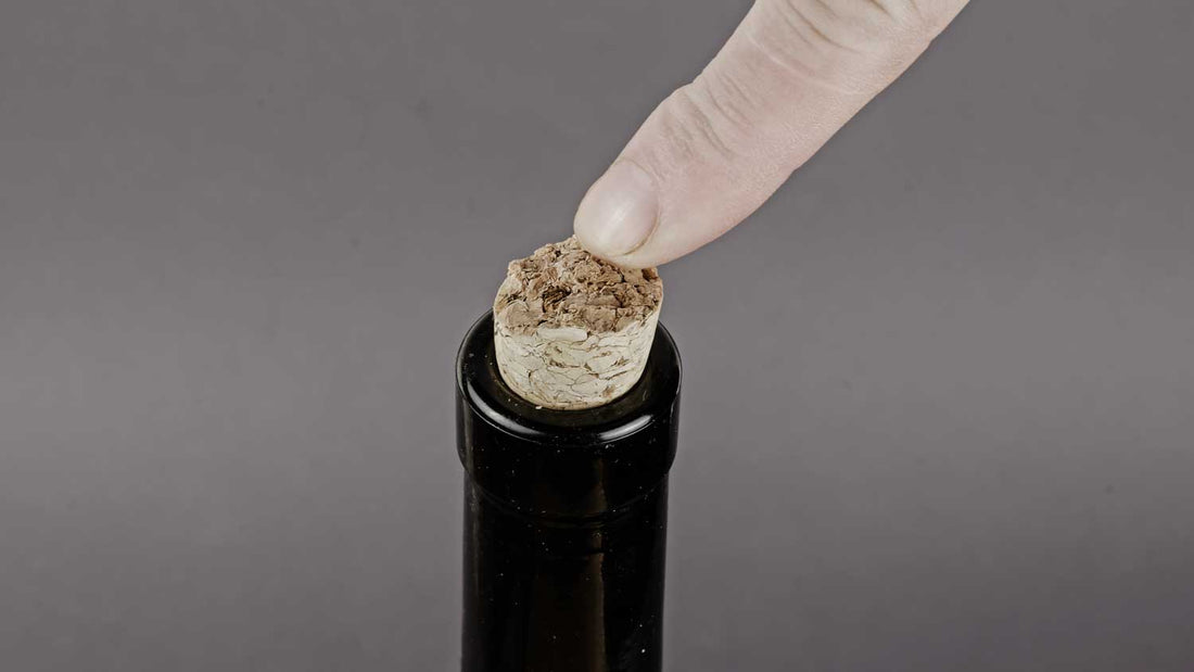 Eine Weinflache neuverkorken, indem man mit dem Finger auf den Korken einer Weinflache drückt.
