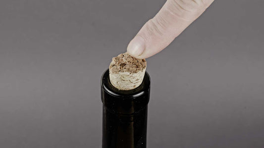Eine Weinflache neuverkorken, indem man mit dem Finger auf den Korken einer Weinflache drückt.