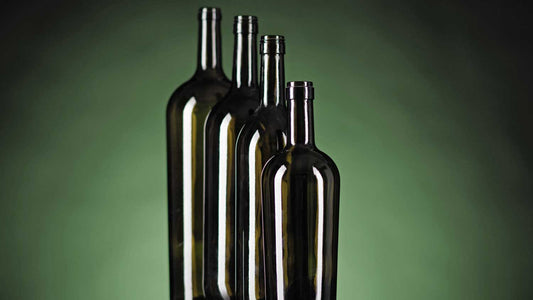 Verschieden große und leere Weinflaschen auf grünem Hintergrund