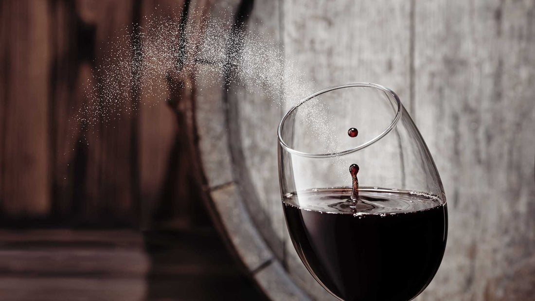 Zucker in einem Glas Rotwein vor einem Holzfass