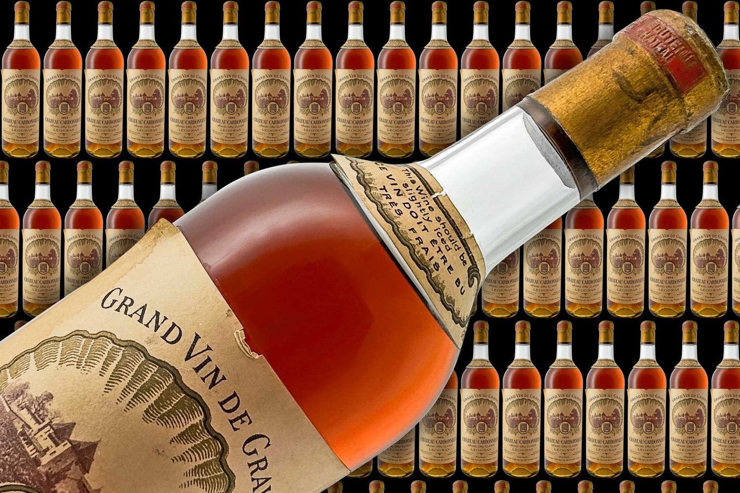 Viele Flaschen Wein im Hintergrund und eine große Weinflasche mit Weißwein im Vordergrund