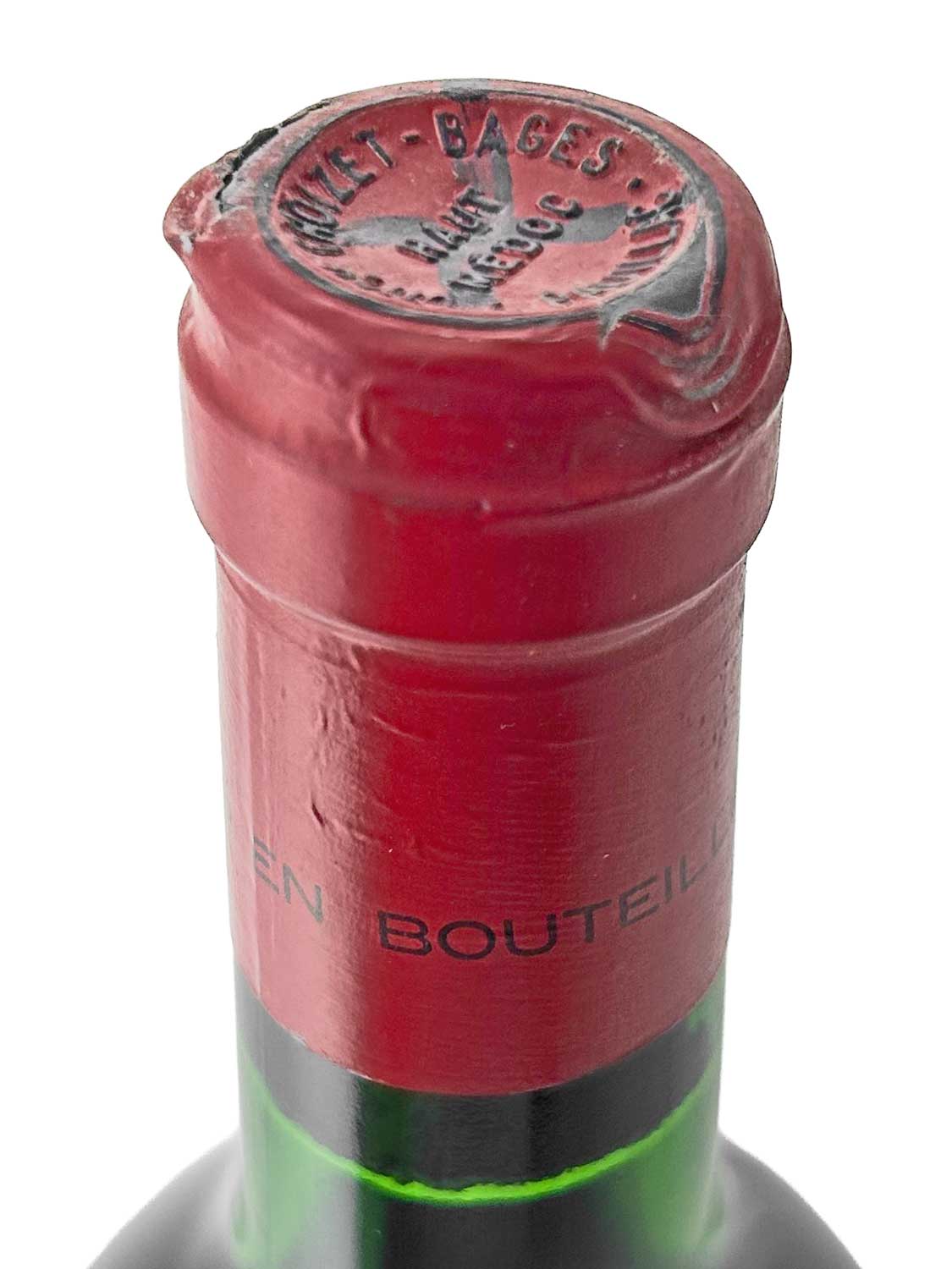 Nahaufnahme des Flaschenhalses einer Weinflasche mit rotem Kapselverschluss, auf dem 'CHATEAU CROIZET-BAGES' und 'BAGES' geprägt sind.