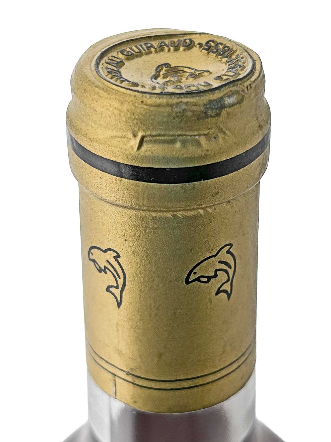 Nahaufnahme des goldfarbenen Flaschenhalses eines Château Guiraud 1997 mit zwei stilisierten Delfinmotiven und schwarzem Ring am oberen Rand