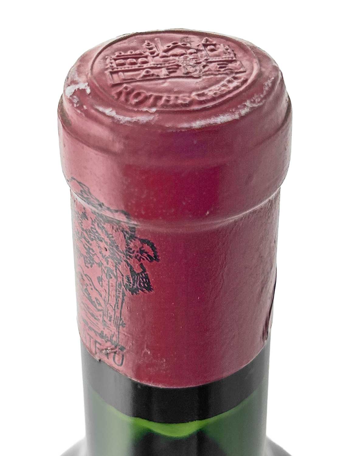 Nahaufnahme des Flaschenhalses einer Weinflasche mit rotem Kapselverschluss und geprägtem Siegel oben, darauf ein Schloss