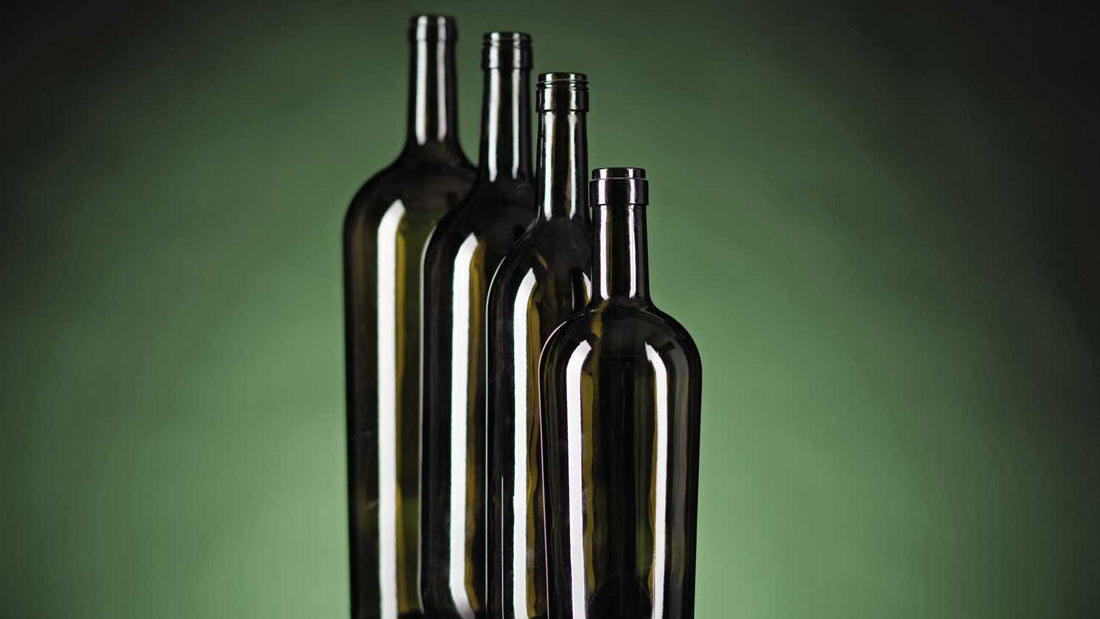 Verschieden große und leere Weinflaschen auf grünem Hintergrund