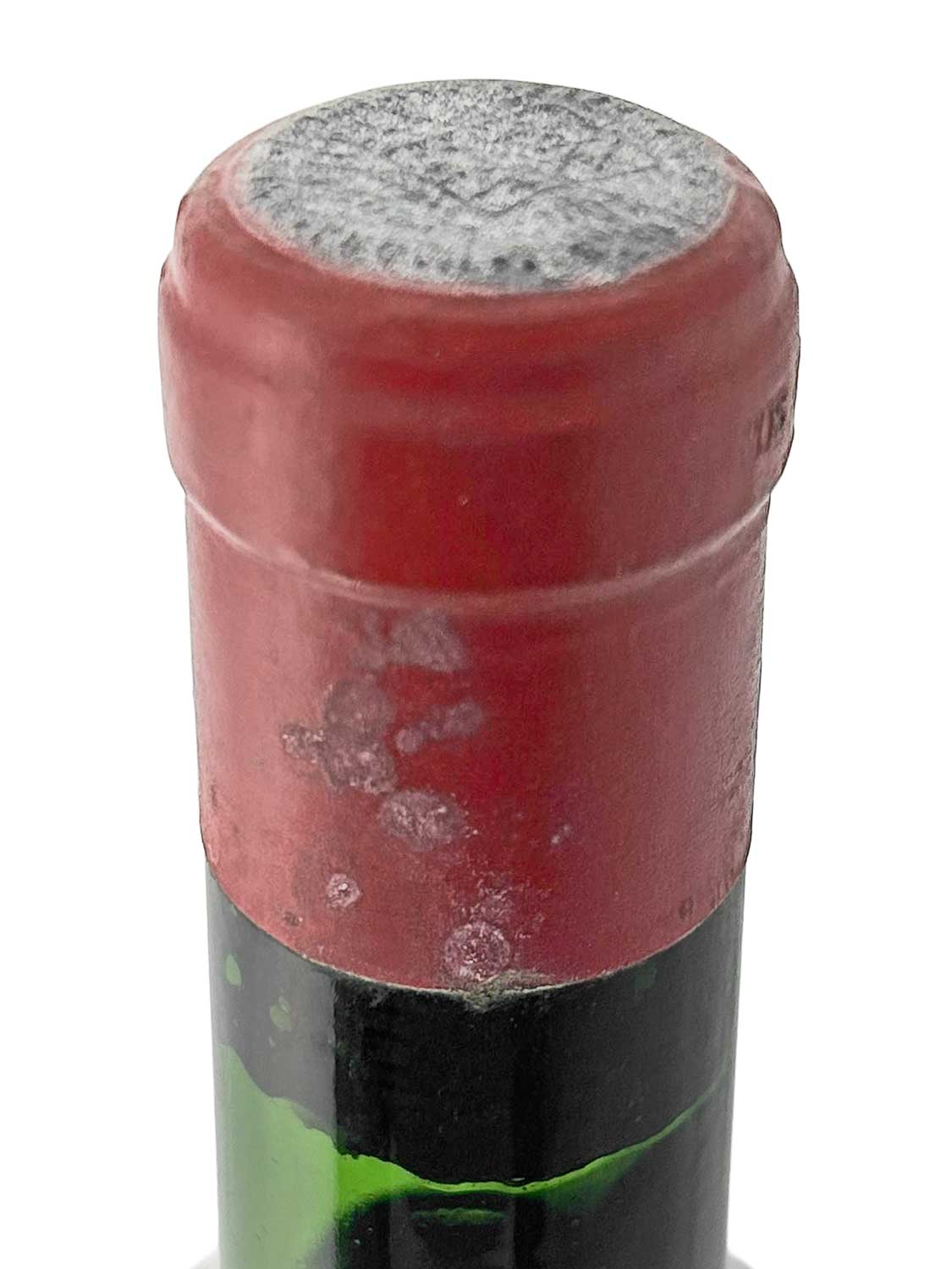 Nahaufnahme des Flaschenhalses eines Weins mit rotem Kapselverschluss.