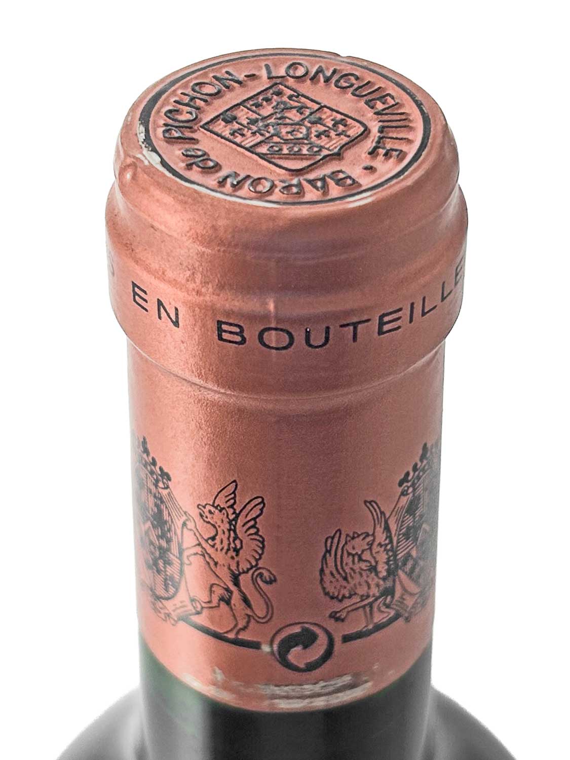 Nahaufnahme des Flaschenhalses eines Château Baron Pichon Longueville 1998 mit kupferfarbener Kapsel und schwarzer Schrift sowie Wappenmotiven