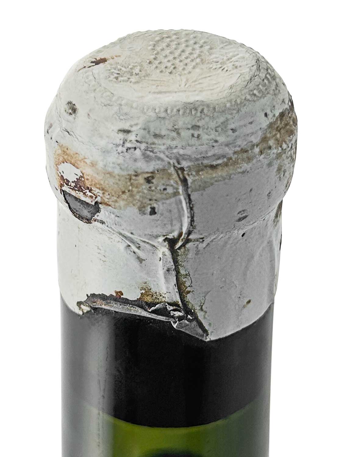 Kapsel einer Weinflasche von Chateau Branaire Ducru 1924, mit beschädigtem, grauem Verschluss und sichtbaren Abnutzungsspuren.