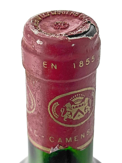 Nahaufnahme des Flaschenhalses einer Weinflasche mit rotem Kapselverschluss, darauf ein goldfarbenes Wappen mit zwei Löwen und der Aufschrift 'EN 1855' sowie teilweise sichtbarem Text 'CAMENSAC'