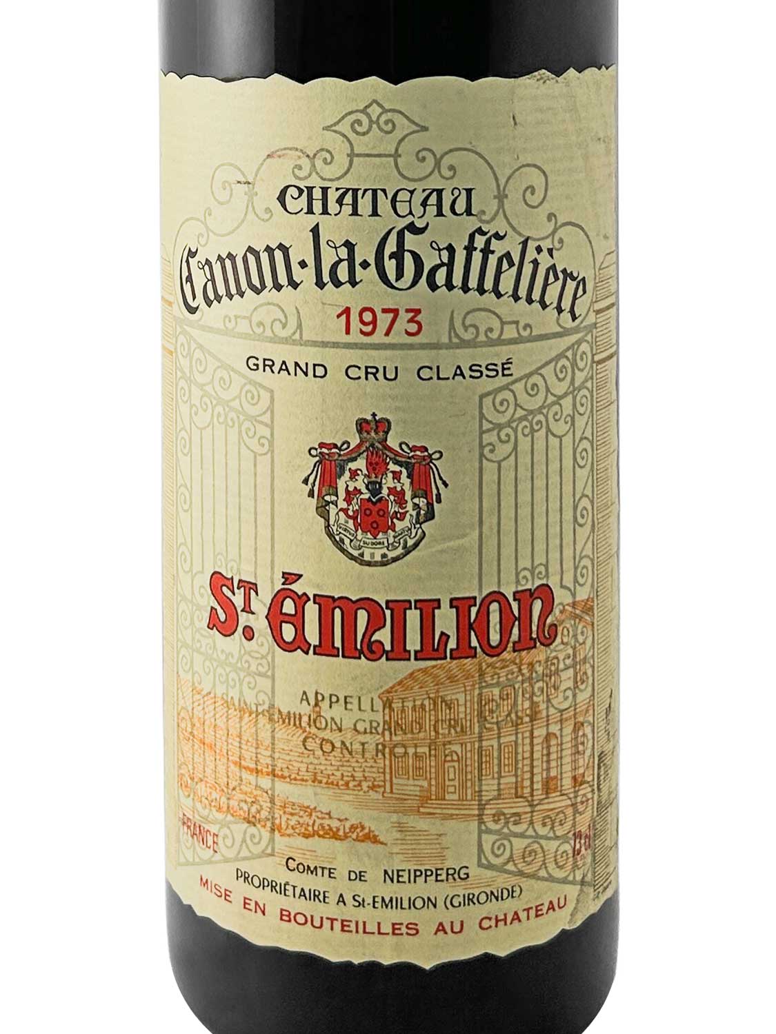 Weinflasche mit Etikett von Château Canon la Gaffelière 1973, Grand Cru Classé, St. Émilion, mit Wappen und dekorativem Tor im Hintergrund