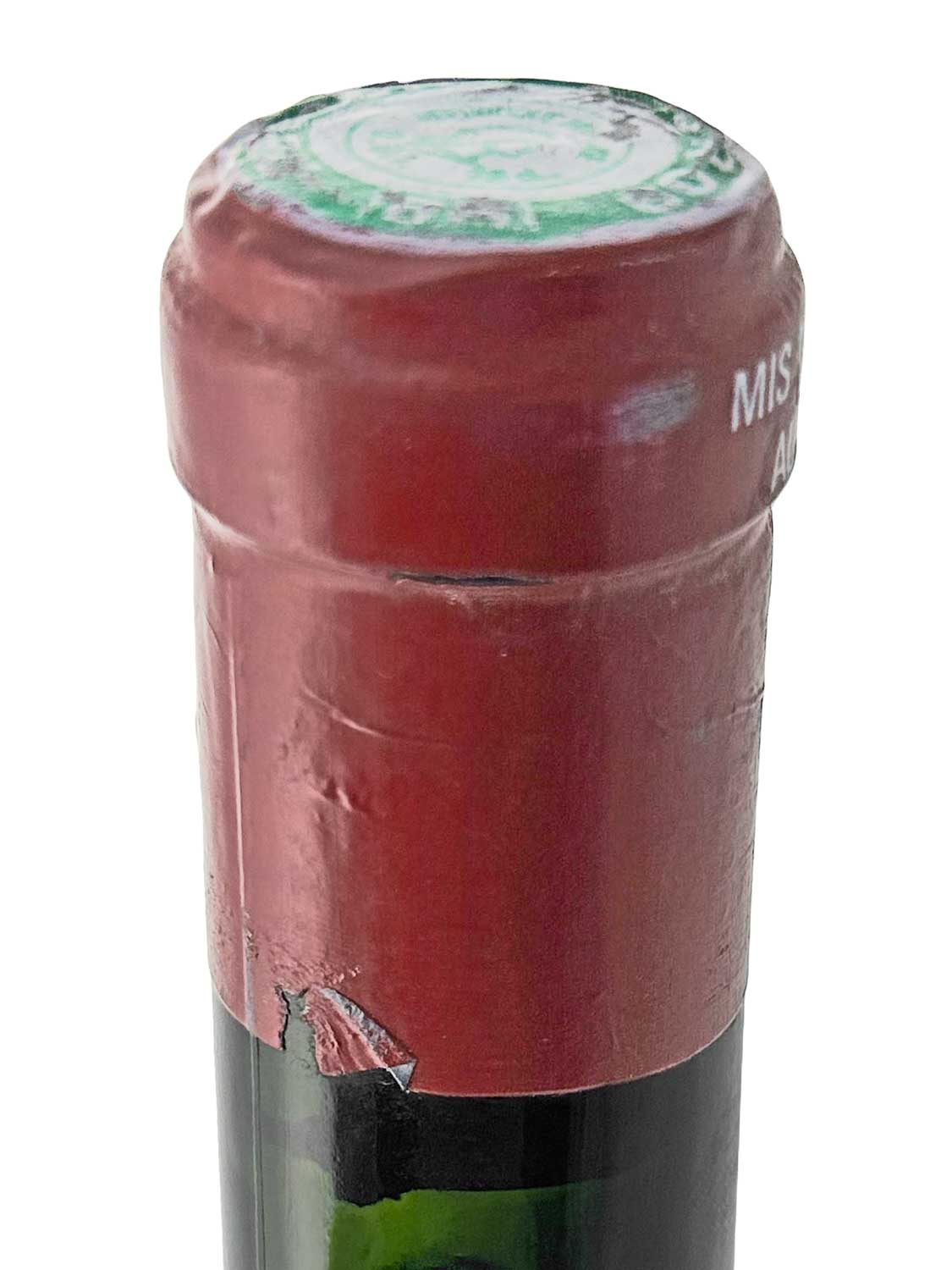 Flaschenkorken mit rotem Siegel und grün-weißem Aufdruck auf der Oberseite, teilweise beschädigt.