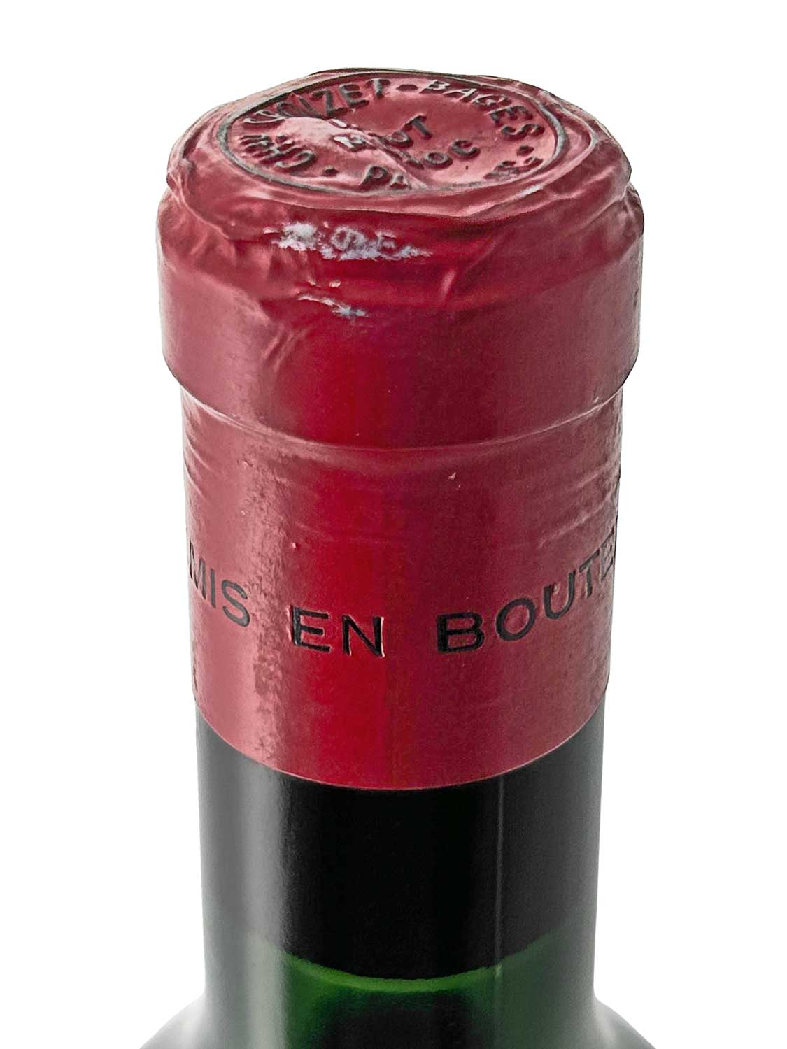 Nahaufnahme des Flaschenhalses einer Weinflasche mit rotem Kapselverschluss und geprägtem Siegel auf dem Kapselkopf.