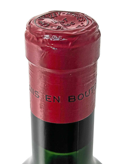 Nahaufnahme des Flaschenhalses einer Weinflasche mit rotem Kapselverschluss und geprägtem Siegel auf dem Kapselkopf.