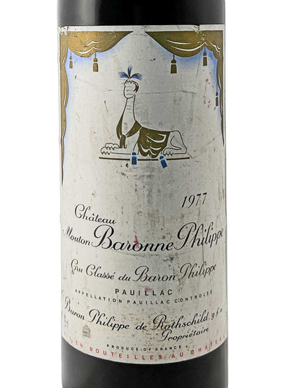 Weinflasche Château Mouton Baronne Philippe 1977 mit Etikett, das eine stilisierte Figur eines liegenden Tieres zeigt.