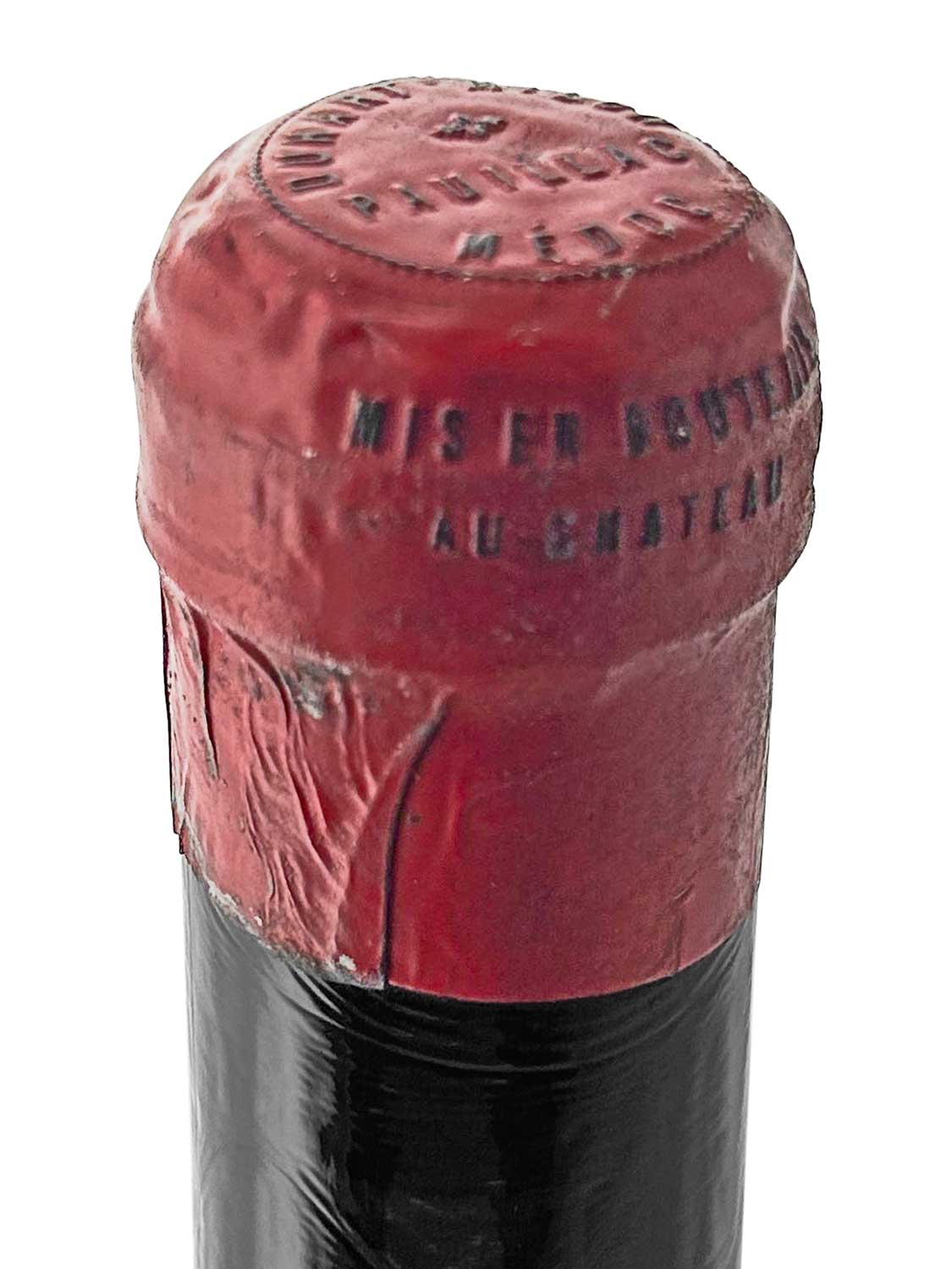 Flasche Chateau Duhart Milon 1926 mit roter Kapsel und eingestanztem Text 'Pauillac Médoc' und 'Mis en Bouteille au Chateau'. Der Flaschenhals ist dunkelgrün.