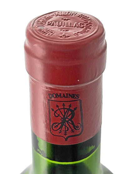 Nahaufnahme des roten Flaschenhalses eines Château Duhart-Milon 1980 Weins mit geprägtem Schriftzug 'PAUILLAC' auf dem Kapselkopf und schwarzem Wappen mit verschlungenen Buchstaben auf dem Hals.