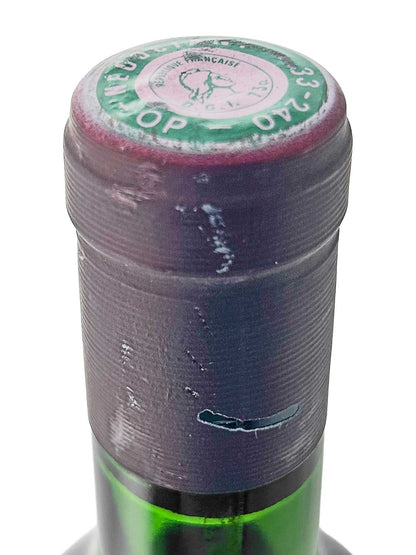 Nahaufnahme des oberen Flaschenhalses eines grünen Weinflasche mit violettem Schrumpfverschluss und einem runden Siegel auf dem Flaschenkopf.