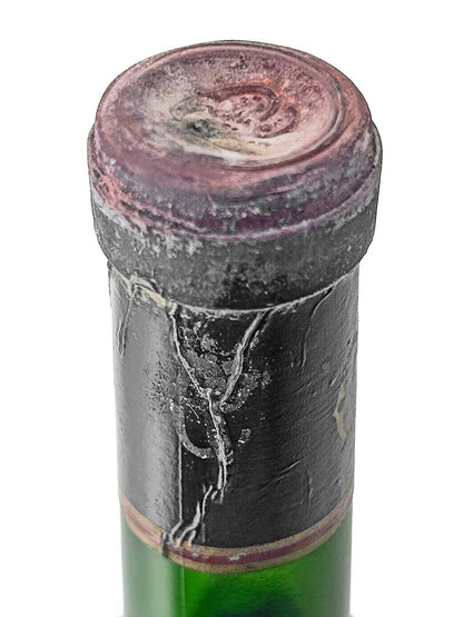 Nahaufnahme des Flaschenhalses einer Weinflasche mit verblasstem, rissigem schwarzen Siegel und einem leicht verschmutzten Korken.