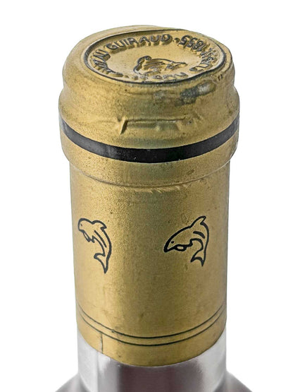 Nahaufnahme des goldfarbenen Flaschenhalses eines Château Guiraud 1997 mit zwei stilisierten Delfinmotiven und schwarzem Ring am oberen Rand