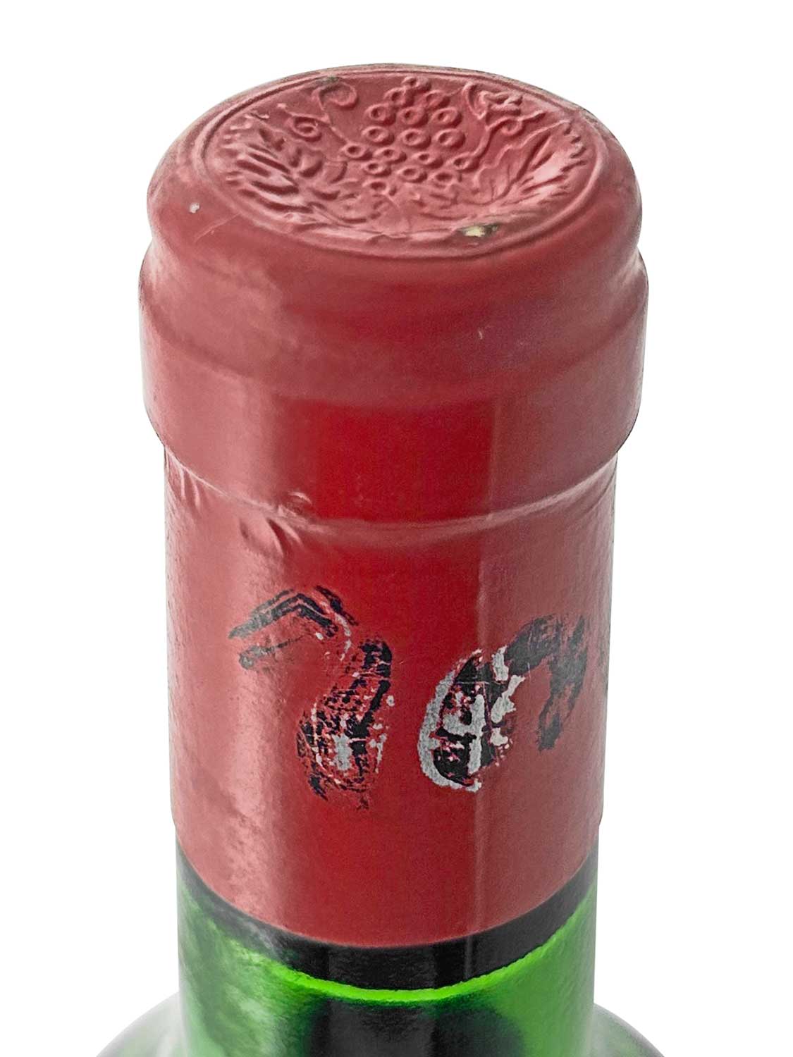 Grüner Weinflaschenhals mit rotem Kapselverschluss, geprägt mit Traubenmotiv, teilweise abgeblätterte schwarze Schriftzeichen auf der Kapsel.