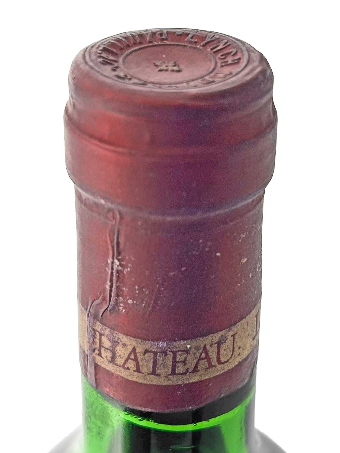 Nahaufnahme des Flaschenhalses einer grünen Weinflasche mit rotem Kapselverschluss und dem Schriftzug 'CHATEAU'.