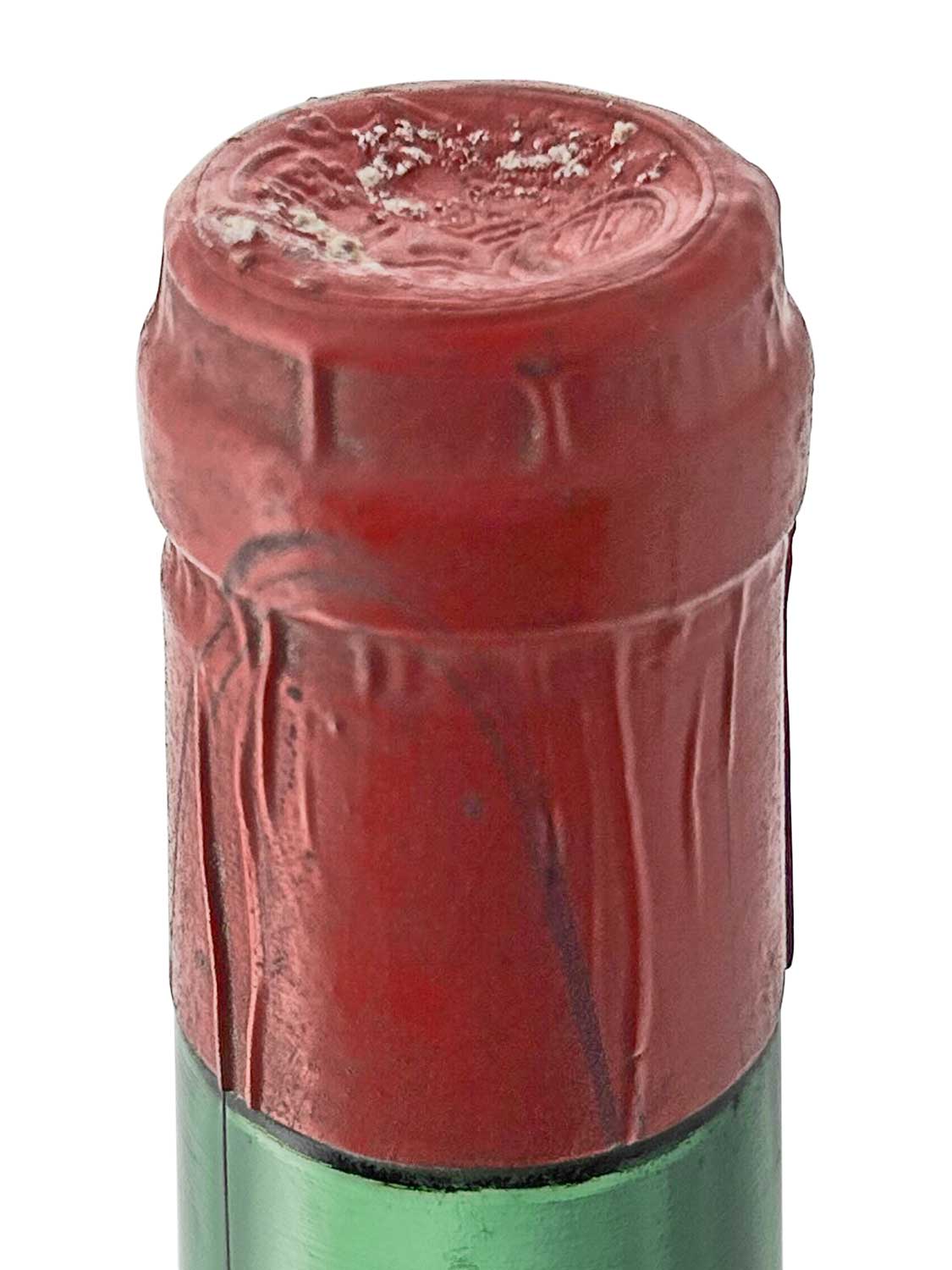Draufsicht auf eine Flasche von Chateau Magdelaine 1955 mit roter Kapsel und grünem Glas. Der Korken ist teilweise sichtbar.