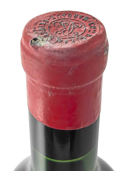 Flasche mit roter Kapsel am Flaschenhals, oben geprägt mit einem runden Siegel und Buchstaben.