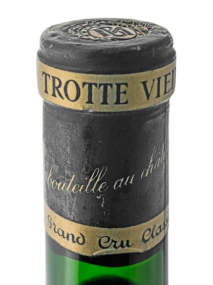Flaschenhals eines grünen Weins mit schwarzem Kapselverschluss, goldfarbenem Etikett mit schwarzer Aufschrift 'TROTTE VIEILLE' und handschriftlicher Schrift auf schwarzem Hintergrund.